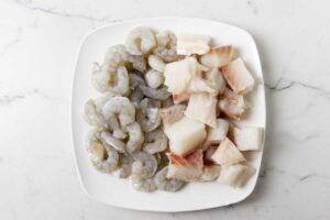 Seasoning slices of white fish and shrimp.