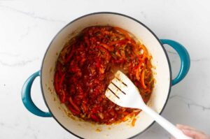Adding tomatoes to the stock pot.