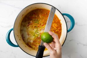 Adding lime zest to moqueca stew.