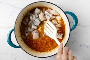 Adding fish and shrimp to the stew.
