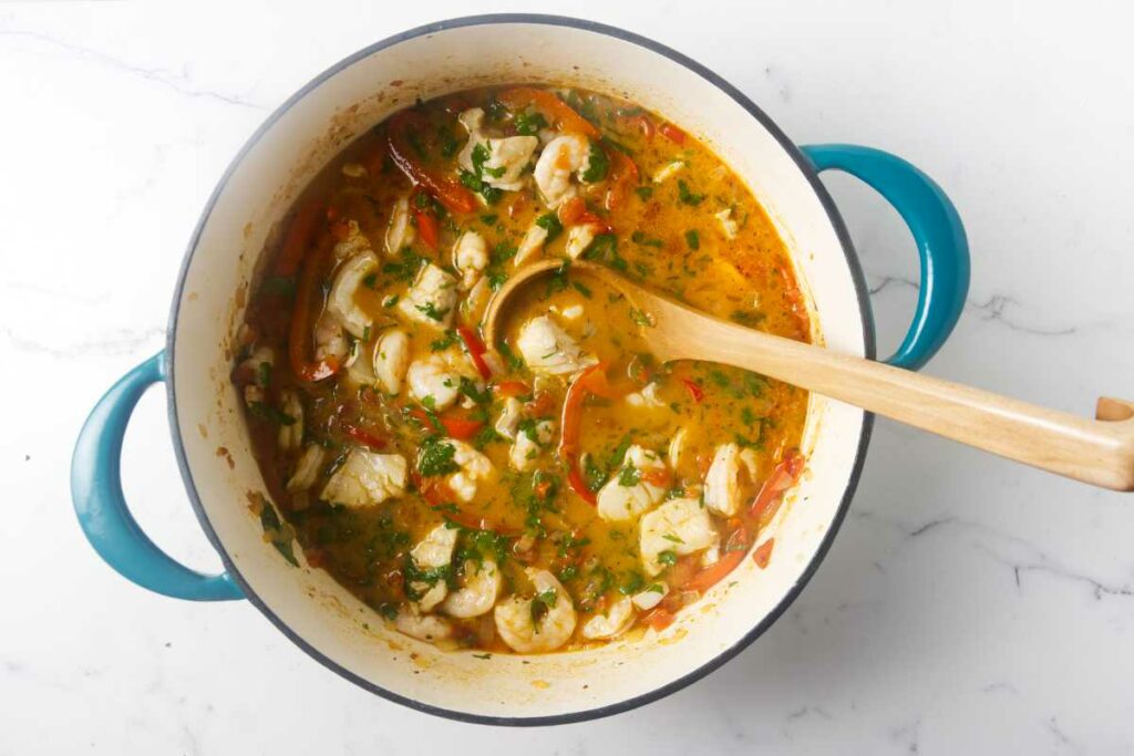 A wooden ladle in a pot of fish and shrimp stew.