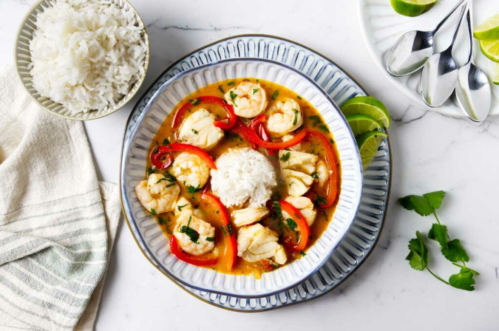A bowl filled with Brazilian fish stew next to white rice.