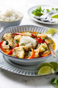 Rice and Brazilian fish stew in a soup bowl next to lime slices.