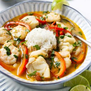 A bowl filled with Brazilian fish stew and a serving of rice.