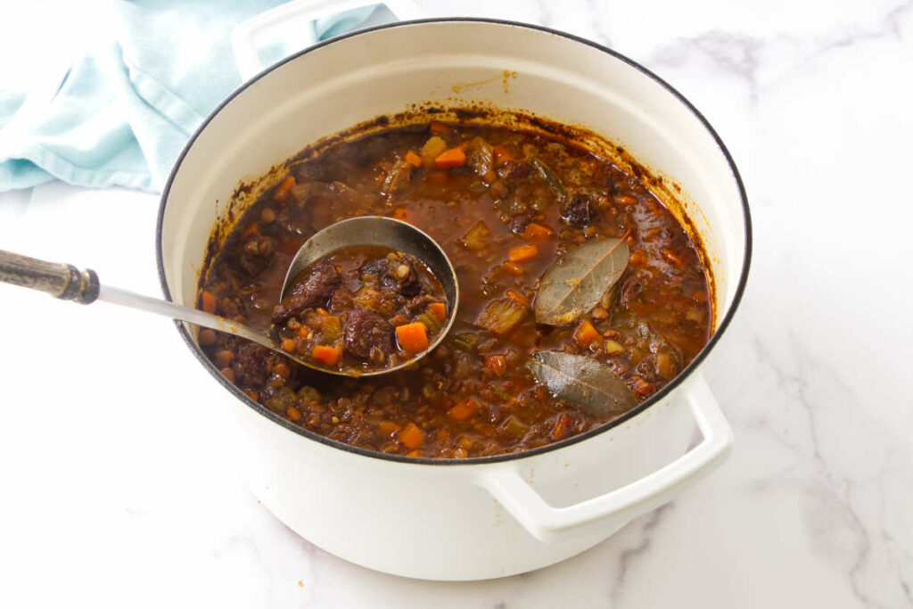 A ladle scooping soup from a stock pot.
