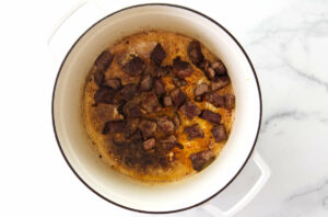Seared chunks of beef in a stock pot.