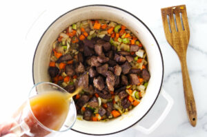 Adding the broth to the soup pot.