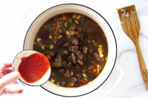 Adding spices and tomato to the soup.
