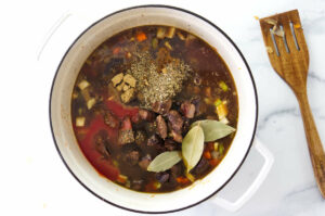 Adding the seasonings to the lentil beef soup.