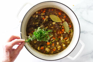 Placing fresh herbs in the beef lentil soup.
