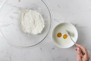 Flour in one bowl and eggs and milk in another dish.
