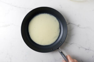 Adding crepe batter to a hot skillet.