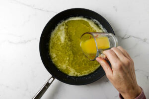 Pouring orange juice into the skillet.