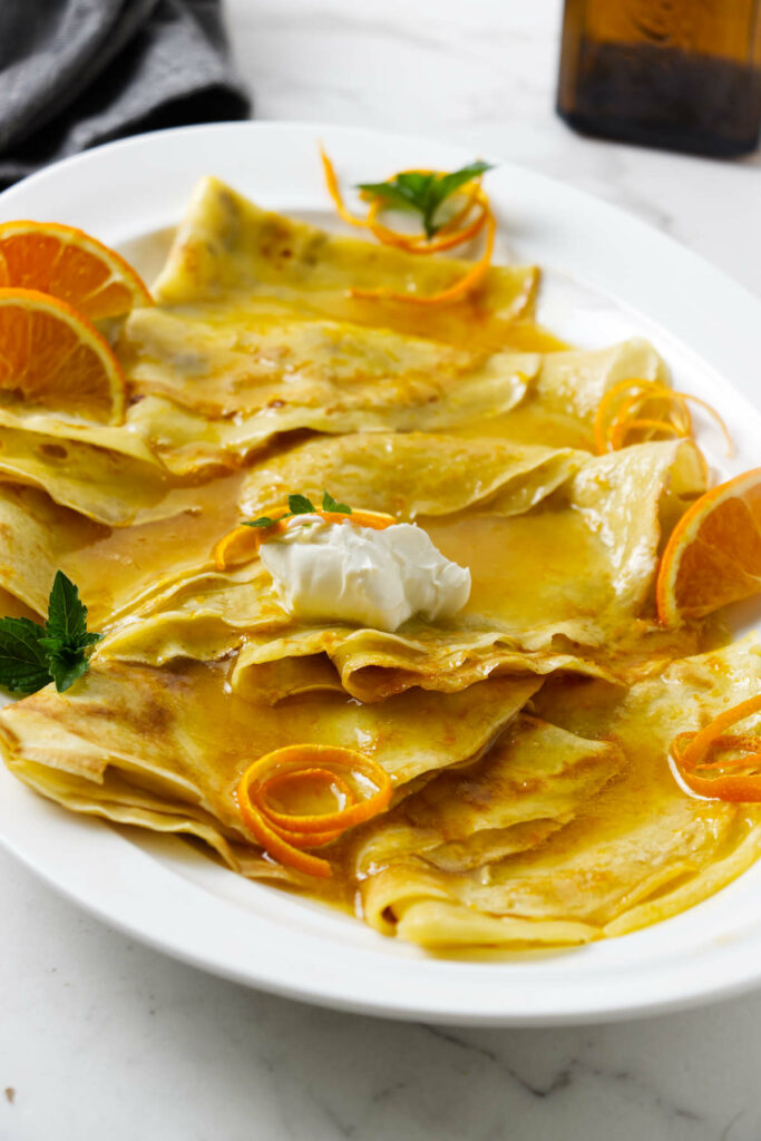 Whipped cream on top of several crepes with crepe suzette sauce.