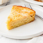A slice of sourdough apple cake on a dessert plate with a fork.