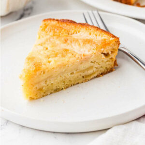 A slice of sourdough apple cake on a dessert plate with a fork.