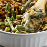 A green bean casserole with fresh green beans in a white dish.