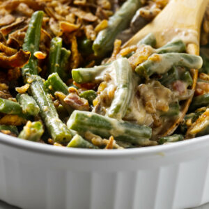 A green bean casserole with fresh green beans in a white dish.