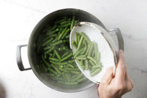 Adding fresh green beans to boiling water.