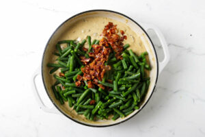 Adding fresh green beans and crispy bacon to the sauce for a casserole.