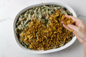 Spreading crispy onions on top of the green bean casserole.
