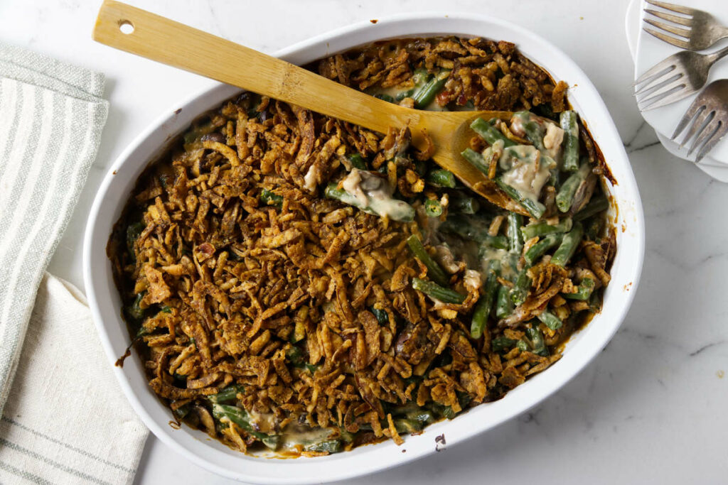 A wooden spoon scooping a serving of green bean casserole.