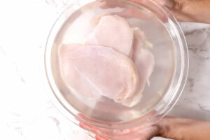 Brining chicken in a bowl of salt water.