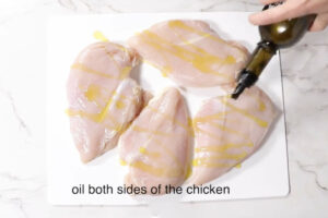 Coating chicken breasts in olive oil.