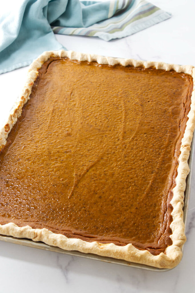 A half sheet pan with a freshly baked pumpkin pie.