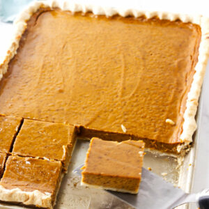 Slices of pumpkin spice pie in a half sheet pan next to a kitchen towel.