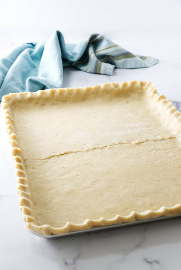 Pie dough formed in a sheet pan with crimped edges.