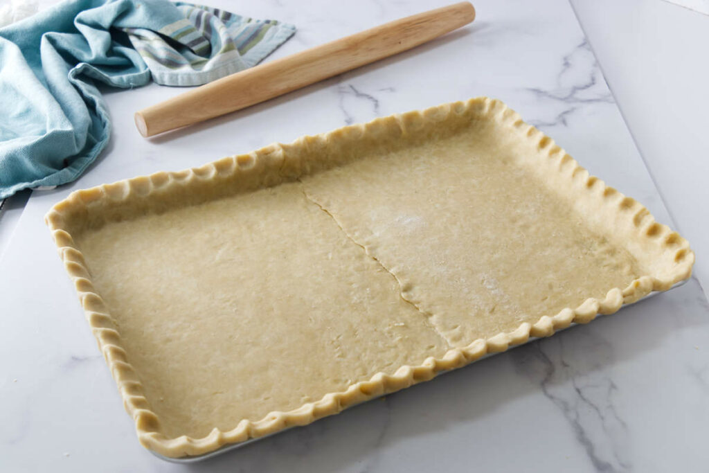 A slab of pie dough in a half sheet pan.