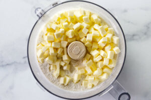 Cubes of butter and some flour in the bowl of a food processor.