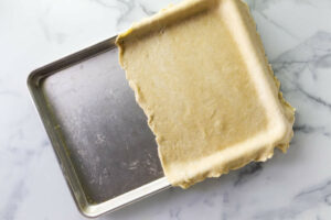 Forming half of the pie dough into a sheet pan.