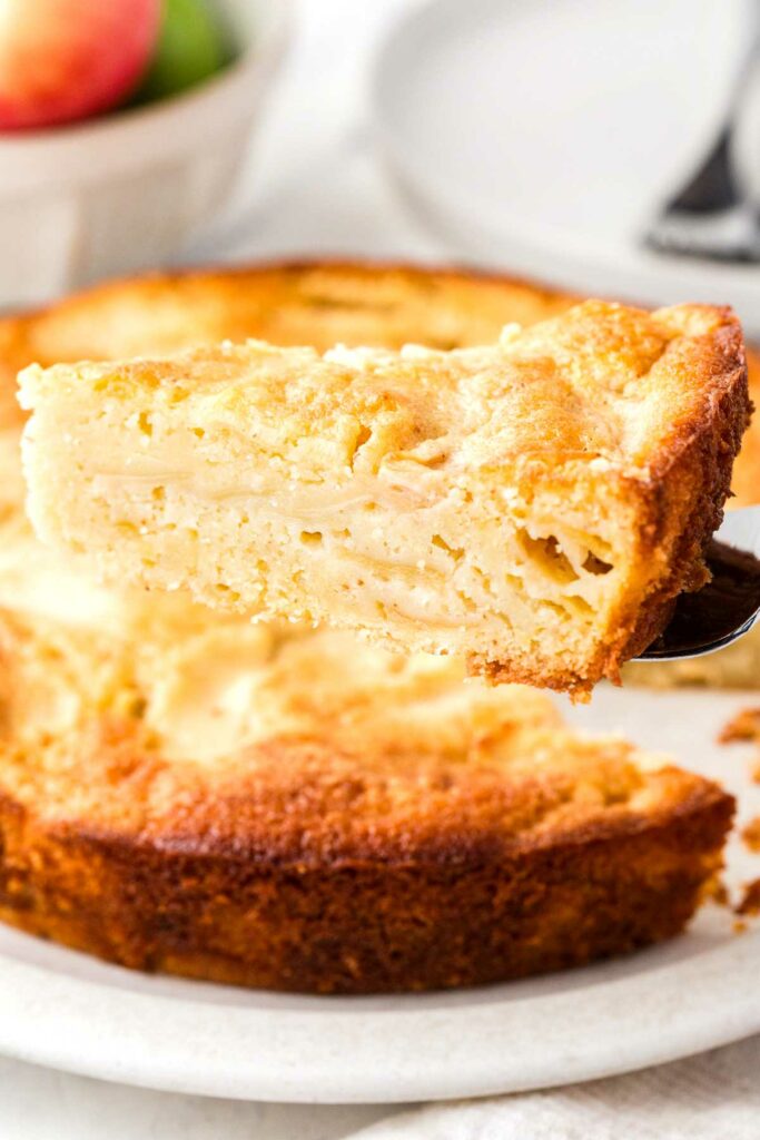 A spatula lifting a slice of apple cake from a dessert platter.