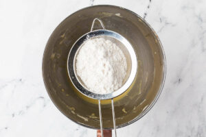 Adding flour to the cake batter.