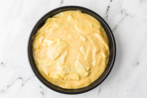 Spreading batter for apple cake into a round cake pan.