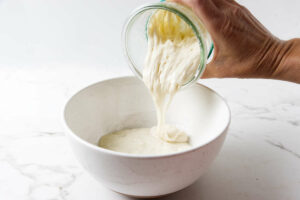 Adding sourdough discard to a mixing bowl.