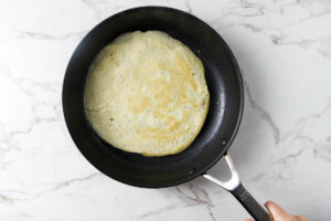 Flipping a cooked crepe in a hot skillet.