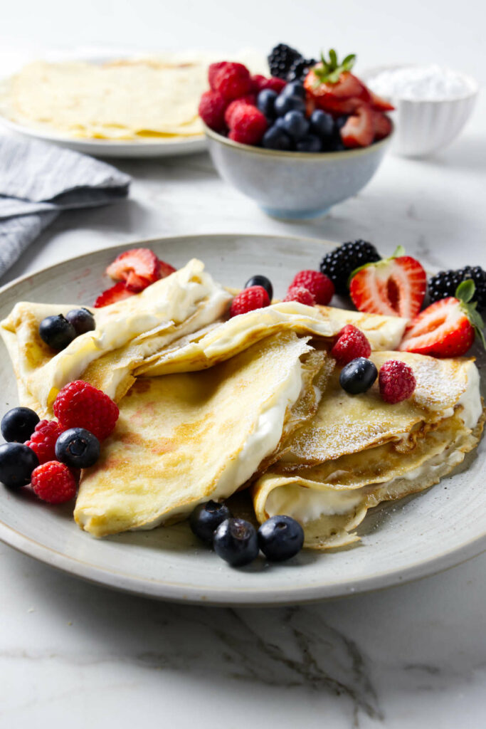 Several sourdough crepes folded in quarters and topped with fruit.
