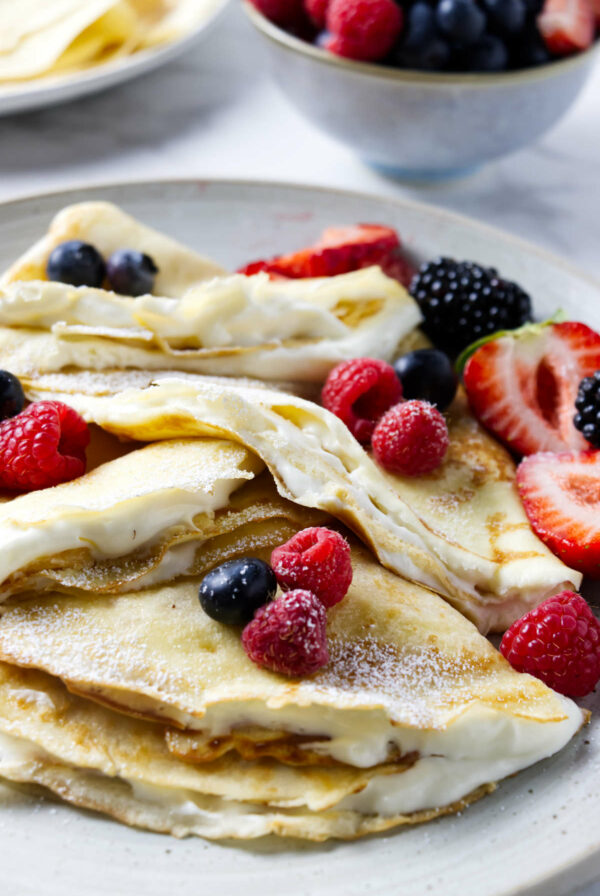 Several sourdough discard crepes filled with whipped cream and fruit.