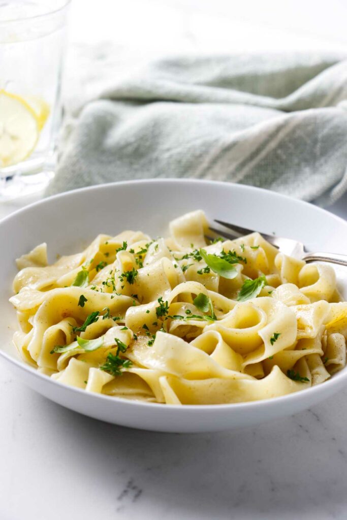 A dinner bowl of sourdough pasta and a glass of lemon water.