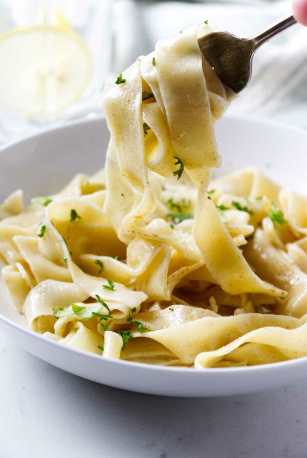 A fork lifting pasta from a bowl.