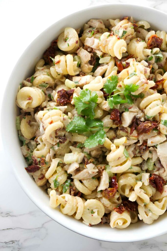 Pasta salad in a bowl with chicken and spicy chipotle sauce.