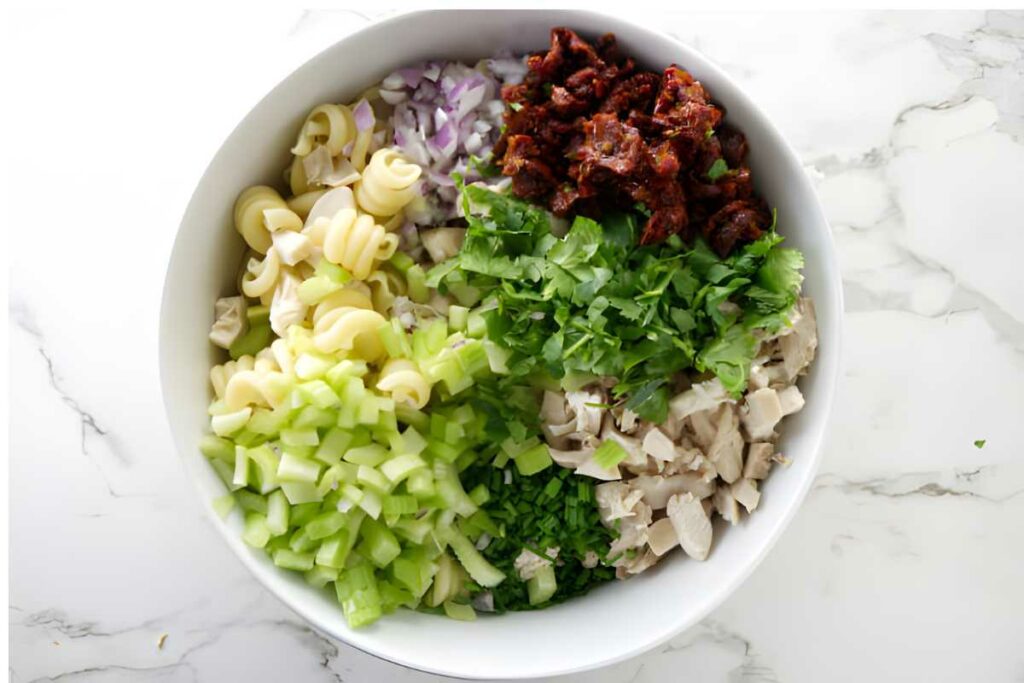 A bowl filled with all the ingredients for a pasta salad.