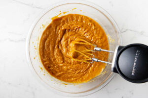Using an electric mixer to puree mashed sweet potatoes.