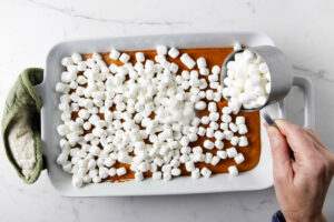 Topping the hot casserole with mini marshmallows.