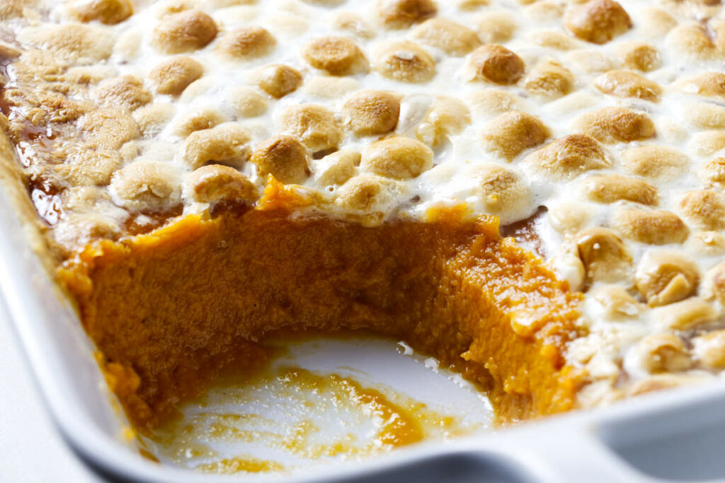 A sweet potato and marshmallow casserole in a white dish.