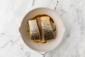 Two fillets of salmon in a skillet to make teriyaki fish recipe.