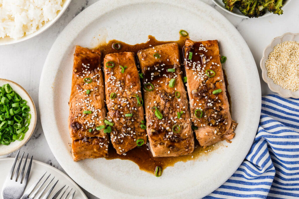 Four servings of teriyaki salmon pan fried and garnished with green onions.